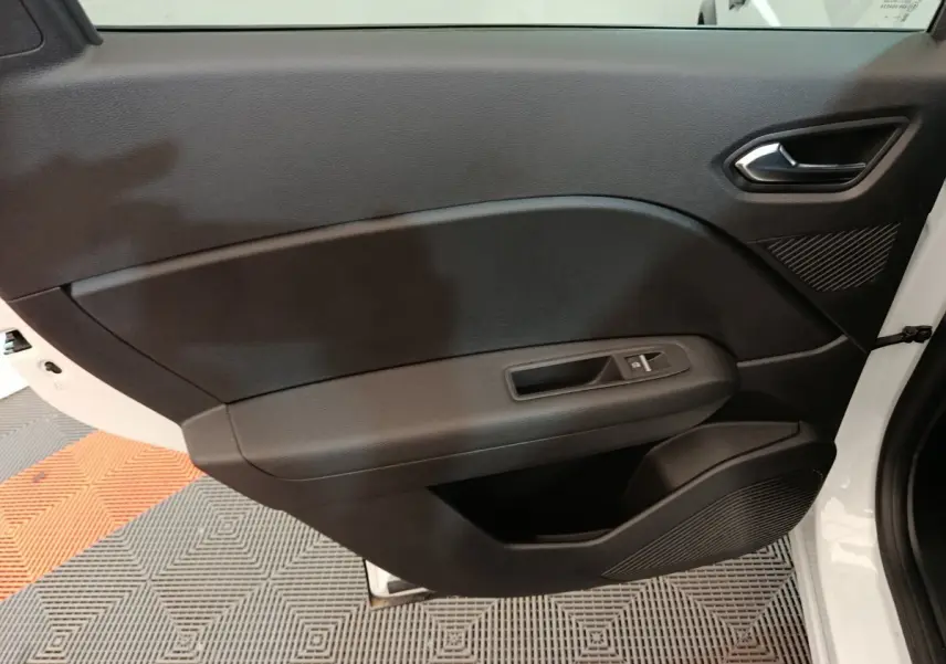 Vue intérieure côté gauche de la porte avant noire du Renault Captur blanc techno E-Tech 2025 avec poignée et commande vitre électrique.
