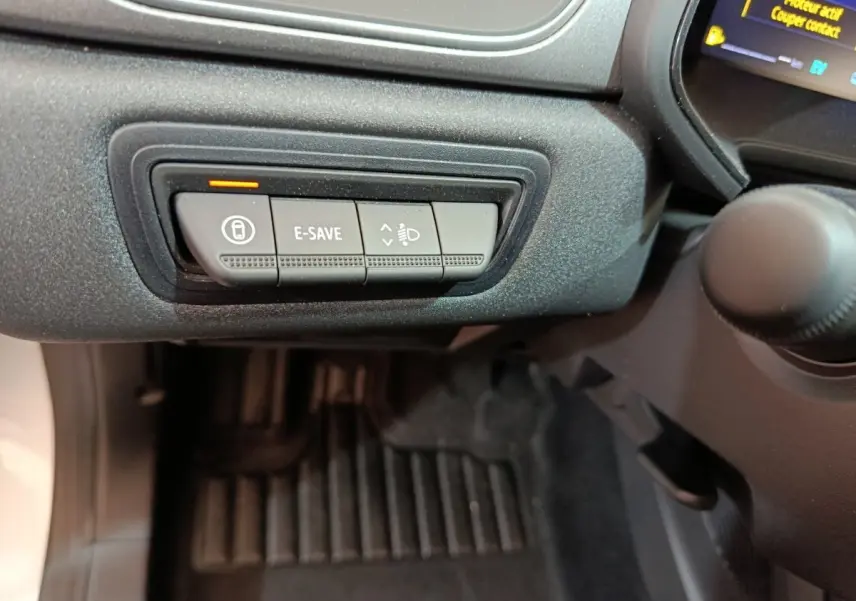 Gros plan sur les commandes sous le tableau de bord côté conducteur du Renault Captur blanc 2025 hybride.