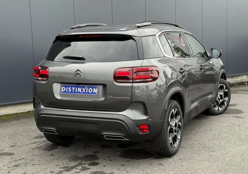 Vue 3/4 arrière droite d'un Citroën C5 Aircross gris Platinium avec jantes alliage bi-ton et toit noir Perla Nera.