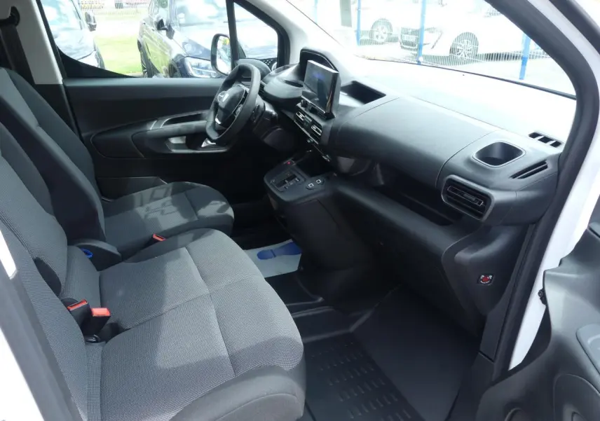 Intérieur avant droit du Peugeot Partner blanc 2025, montrant les sièges tissu et le tableau de bord moderne avec écran tactile.