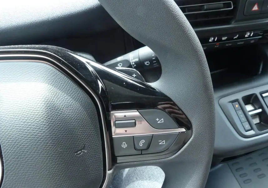 Gros plan sur le volant multifonctions côté droit du Peugeot Partner blanc avec commandes audio et vocales intégrées.