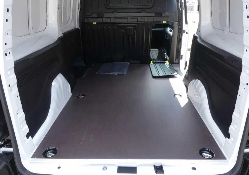 Vue intérieure arrière du Peugeot Partner XL blanc, montrant l'espace de chargement avec plancher bois antidérapant et parois blanches.