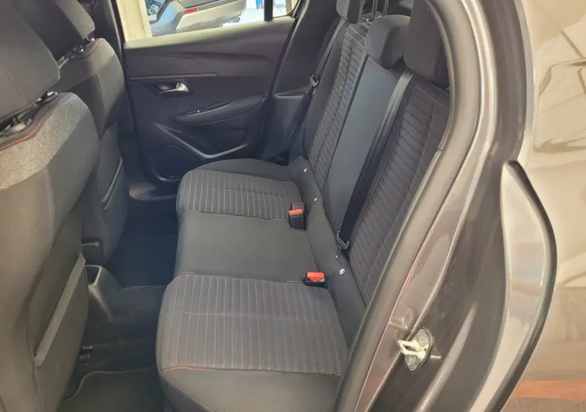 Vue côté droit de l'habitacle arrière gris foncé d'une Peugeot 208 BlueHDi 100 S&S Active Pack 2023 avec sièges tissu rayés.