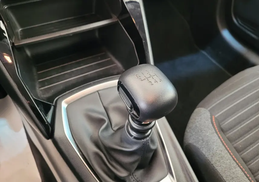 Le levier de vitesses manuel noir de la Peugeot 208 BlueHDi 100 S&S Active Pack avec coutures rouges sur siège tissu gris.