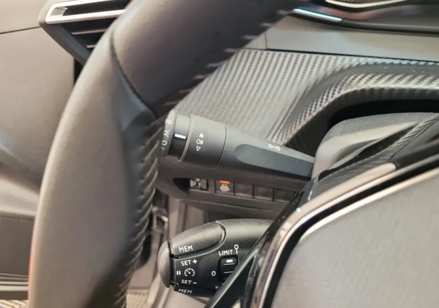 Gros plan sur le volant cuir et commandes au volant de la Peugeot 208 gris foncé version BlueHDi 100 S&S Active Pack 2023.