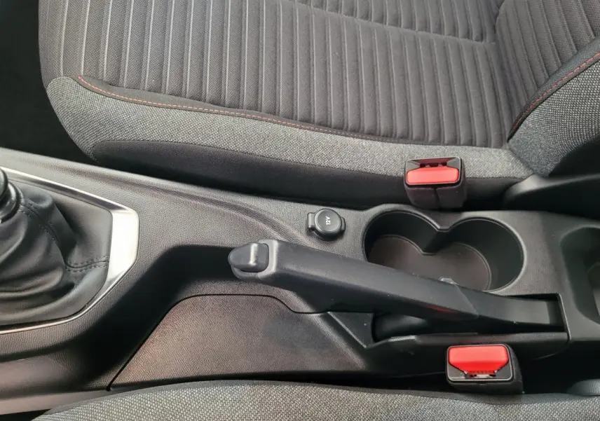 Vue rapprochée de la console centrale de la Peugeot 208 gris foncé, montrant frein à main manuel et porte-gobelets.