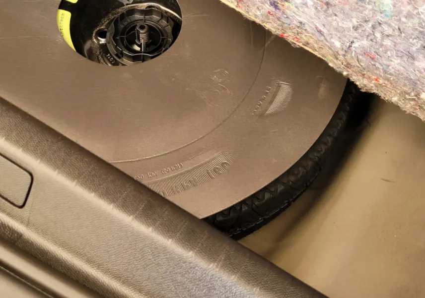 Gros plan sur la roue de secours sous le tapis de coffre d'une Peugeot 208 gris foncé, version BlueHDi 2023.