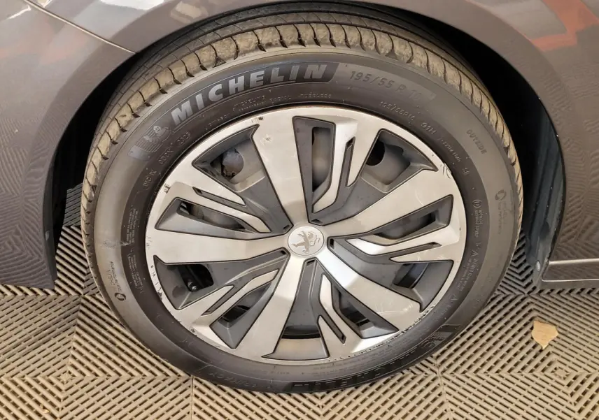 Gros plan sur la roue avant gauche d'une Peugeot 208 gris foncé avec jante alliage et pneu Michelin.