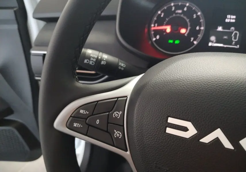 Gros plan sur le volant noir de la Dacia Jogger 2025, montrant les commandes de régulateur de vitesse à gauche.