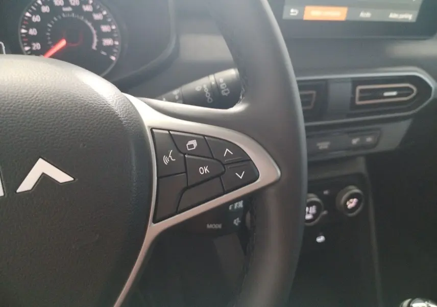 Gros plan sur la partie droite du volant du Dacia Jogger 2025 avec commandes multifonctions et tableau de bord noir.