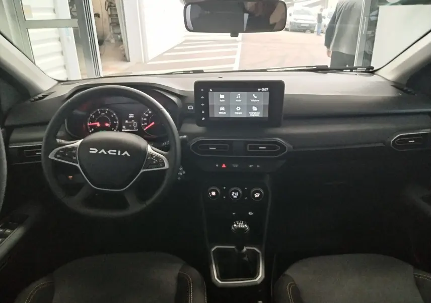 Intérieur du Dacia Jogger 2025, vue frontale du tableau de bord avec écran tactile et volant multifonction noir.