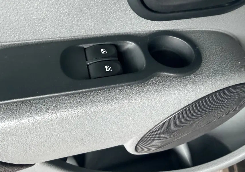 Gros plan sur les commandes de lève-vitres électriques côté conducteur d’un Renault Modus beige, intérieur gris noir.