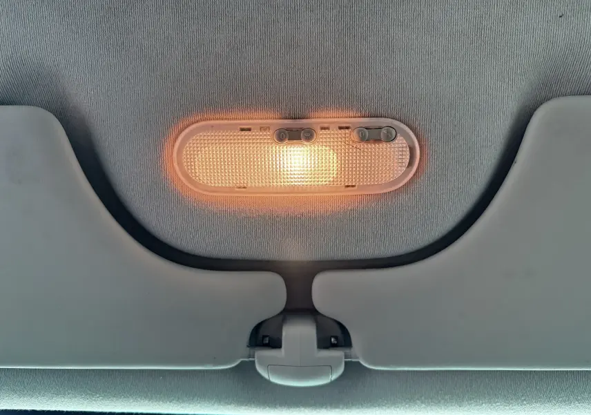 Plafonnier intérieur allumé avec deux pare-soleil gris clair dans une Renault Modus beige de 2011.