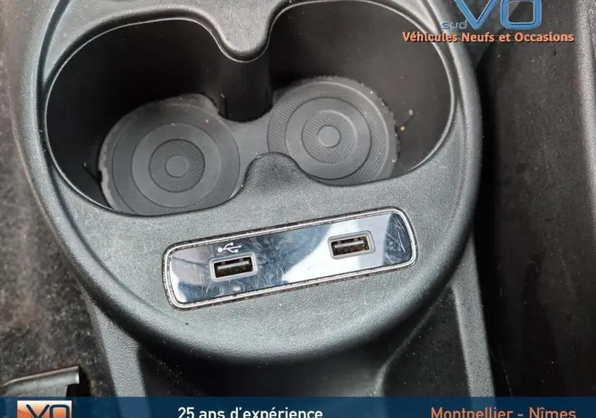 Gros plan sur la console centrale avec porte-gobelets et deux ports USB de la FIAT 500C noire 2024.