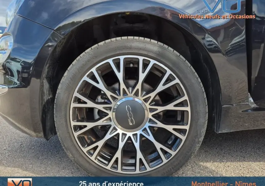 Gros plan sur la roue avant gauche noire d'une FIAT 500C 2024, mettant en valeur la jante multibranches distinctive.