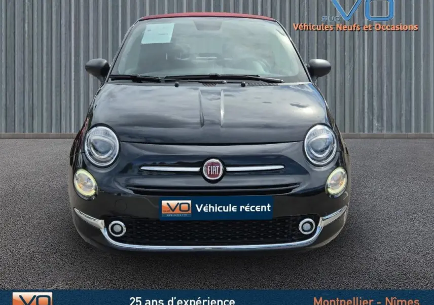Vue avant d'une FIAT 500C noire 2024 avec toit rouge, affichant son logo et ses phares ronds allumés.