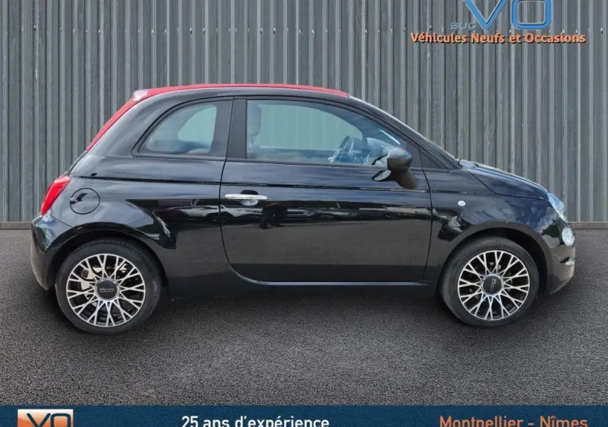 Profil côté droit de la FIAT 500C noire 2024 avec toit rouge et jantes stylisées, vue sur roue de secours intégrée.