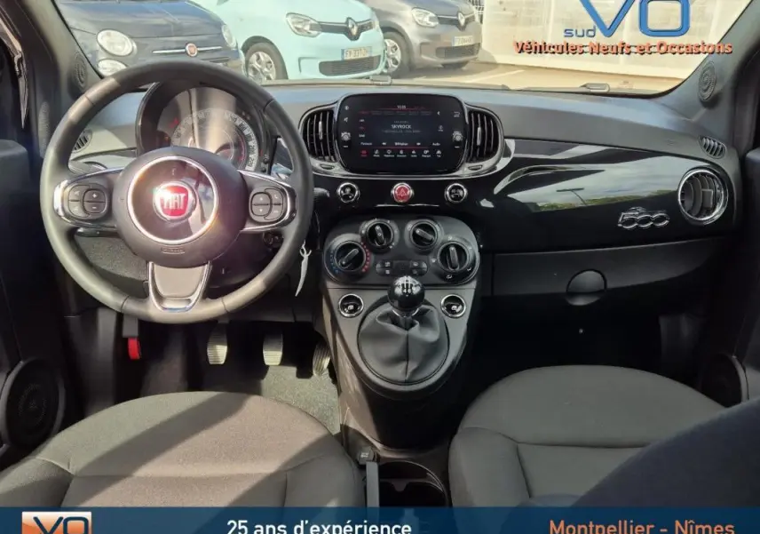 Vue intérieure avant de la Fiat 500C noire 2024, tableau de bord brillant avec logo 500 et volant multifonction.