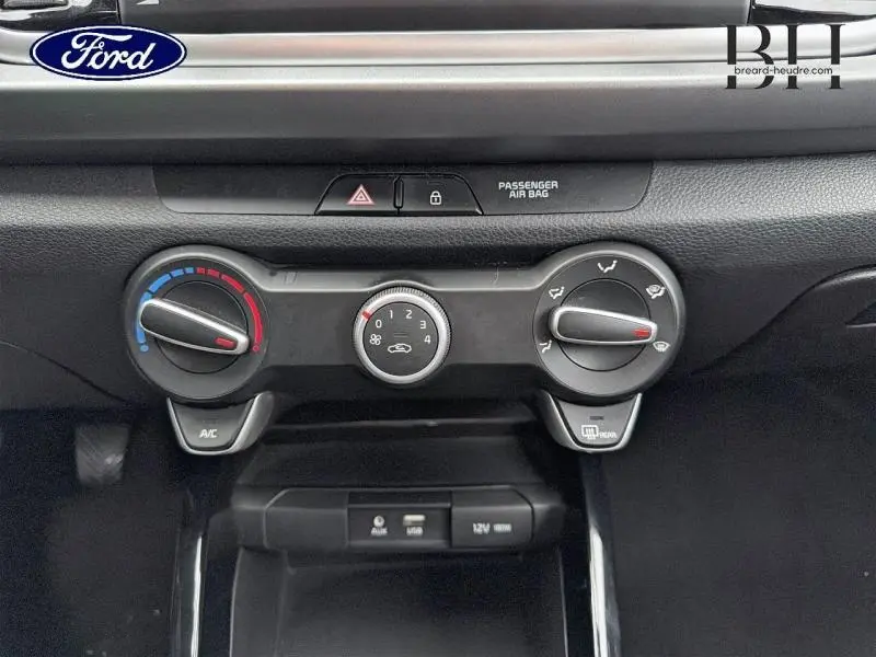 Détail de la console centrale de la Kia Rio 2018 noire, montrant les commandes manuelles de climatisation et les prises auxiliaires.