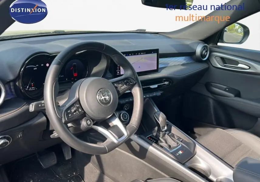 Vue intérieure côté conducteur de l'Alfa Romeo Tonale 2023, tableau de bord moderne avec écran tactile et volant cuir noir.