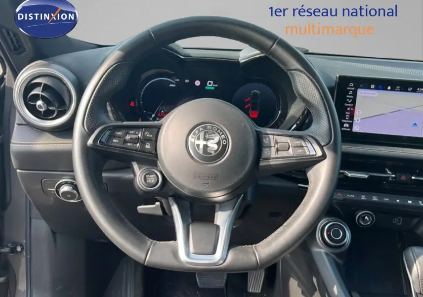 Vue intérieure centrée sur le volant Alfa Romeo Tonale 2023, tableau de bord numérique et écran tactile avec navigation.