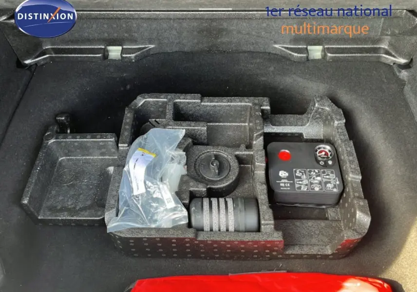 Coffre ouvert d’une Alfa Romeo Tonale gris Vesuvio, vue plongeante sur le rangement avec kit de réparation pneus.