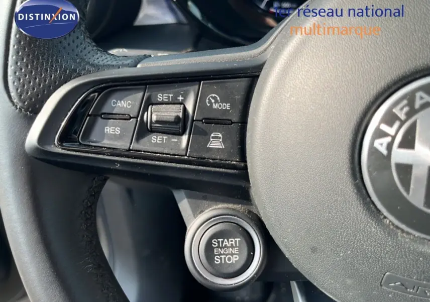 Gros plan sur le volant cuir noir de l'Alfa Romeo Tonale gris Vesuvio, avec commandes de régulateur et bouton start/stop visibles.