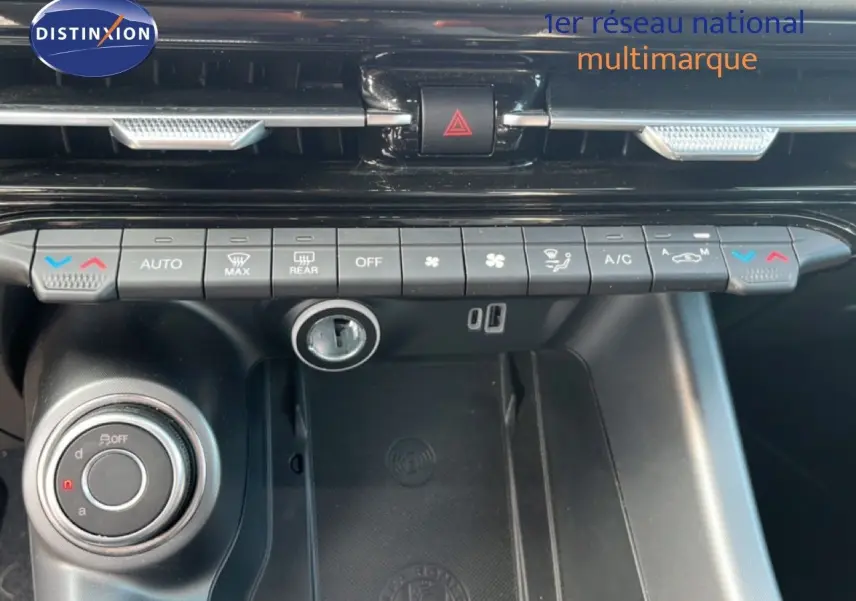 Vue rapprochée de la console centrale de l'Alfa Romeo Tonale gris Vesuvio, montrant les commandes de climatisation et la molette de sélection.