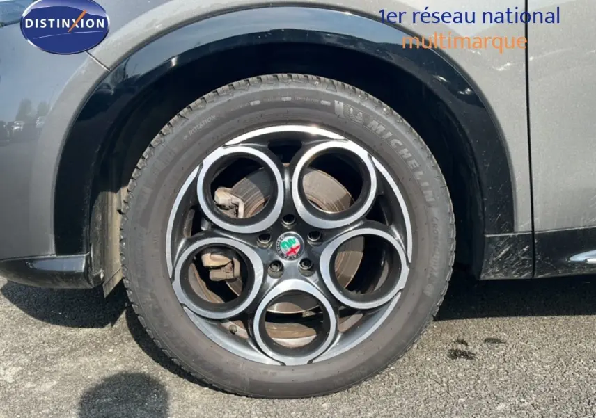 Gros plan sur la roue avant droite d'une Alfa Romeo Tonale gris Vesuvio métal avec jante en alliage à cinq cercles.