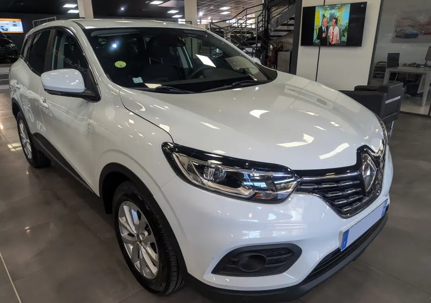 Renault Kadjar Blanc Glacier en 3/4 avant droit, mettant en valeur ses phares modernes et sa calandre noire brillante.
