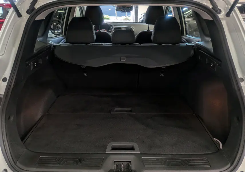 Coffre ouvert vu de l'arrière du Renault Kadjar Blanc Glacier 2021, montrant l'espace de chargement et les sièges arrière.