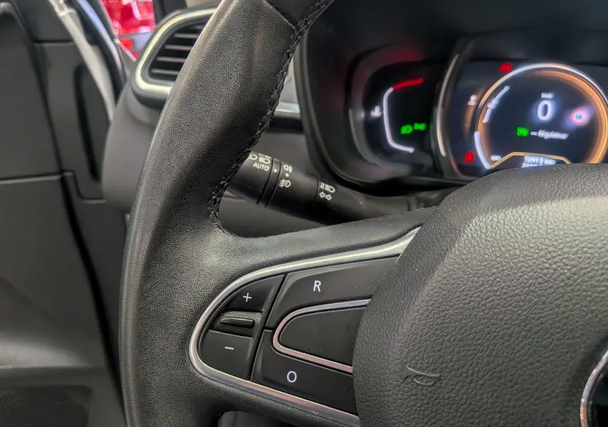 Gros plan sur le volant côté gauche du Renault Kadjar 2021, avec commandes intégrées et tableau de bord numérique en arrière-plan.