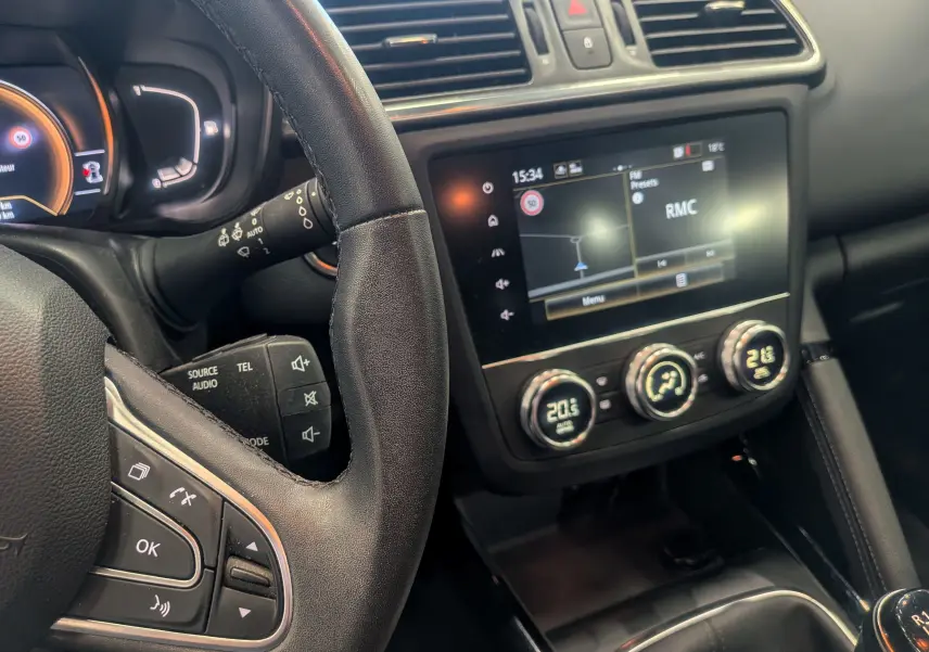 Vue intérieure rapprochée du tableau de bord et du volant noir du Renault Kadjar 2021 avec écran tactile et commandes climatiques.