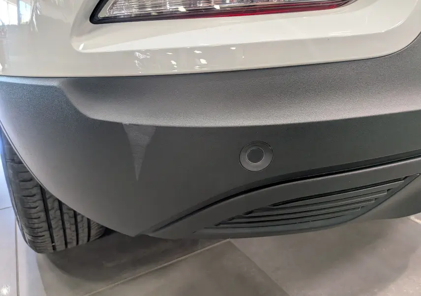 Gros plan sur le pare-chocs arrière noir et blanc glacier du Renault Kadjar Blue dCi 115 CH BUSINESS avec capteur de recul visible.