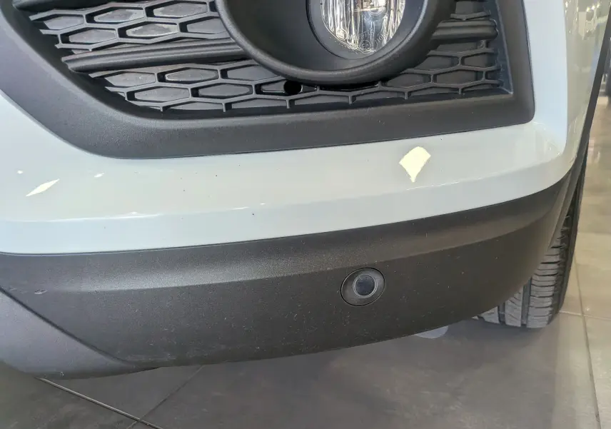 Gros plan sur le pare-chocs avant droit blanc glacier du Renault Kadjar 2021 avec antibrouillard et capteur de stationnement.