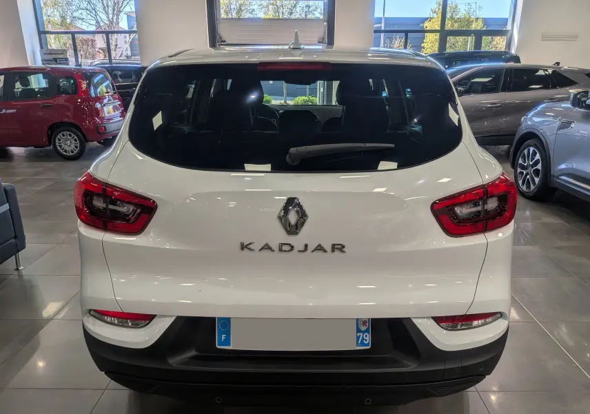 Vue arrière d'un Renault Kadjar blanc Glacier 2021 en showroom, avec feux arrière LED et lunette arrière teintée.