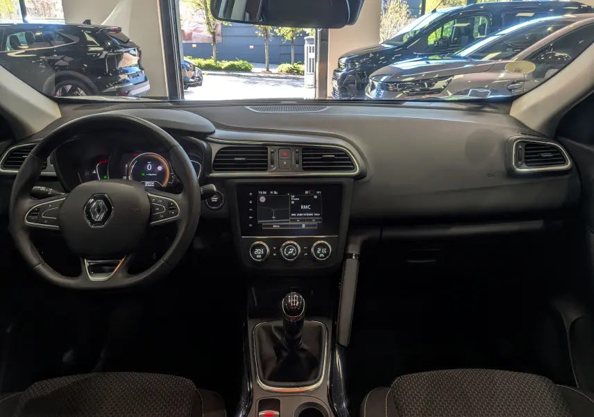 Vue intérieure avant du Renault Kadjar blanc Glacier 2021, tableau de bord avec écran tactile et boîte manuelle visible.