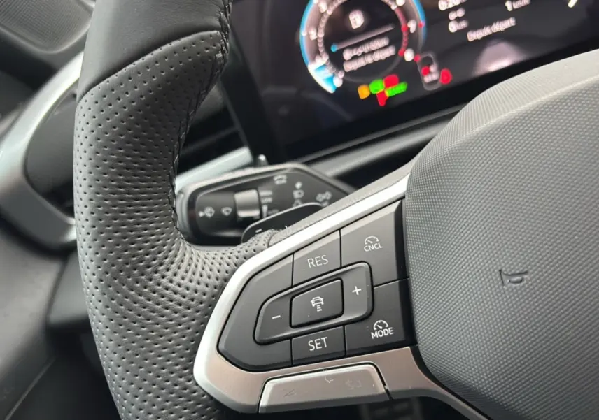 Gros plan sur le volant cuir perforé multifonctions du Volkswagen T-Roc 2026 avec commandes de régulateur adaptatif.