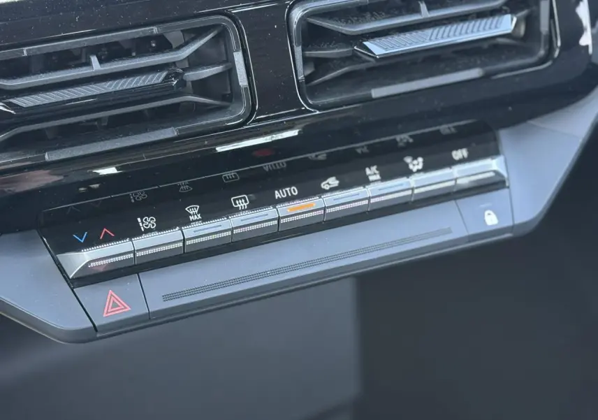 Gros plan sur la console centrale noire de la Renault R5 E-Tech avec commandes climatisation et ventilation.