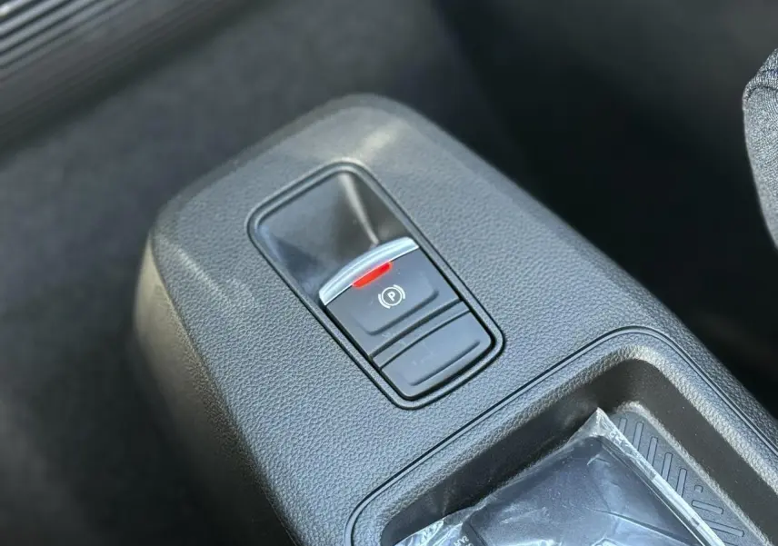 Gros plan sur le frein de parking électrique dans la console centrale d’une Renault R5 E-Tech Electrique blanche.