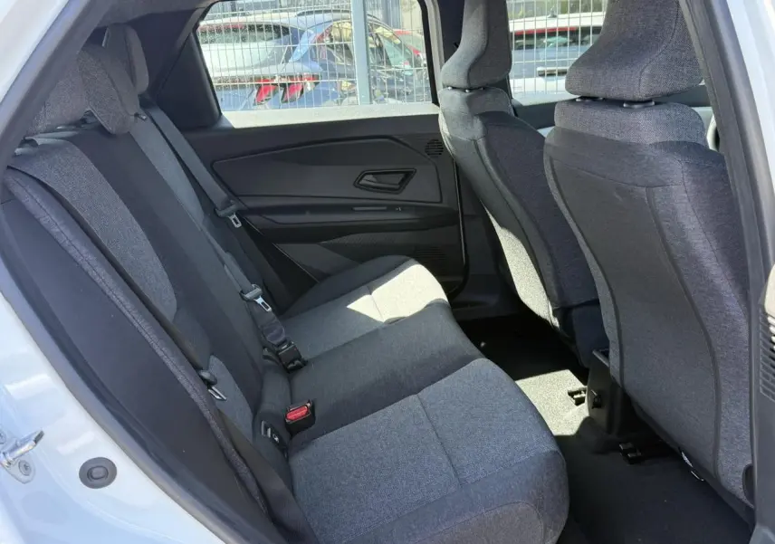 Vue intérieure arrière côté gauche de la Renault R5 E-Tech 2026, sièges tissu gris et portières noires.