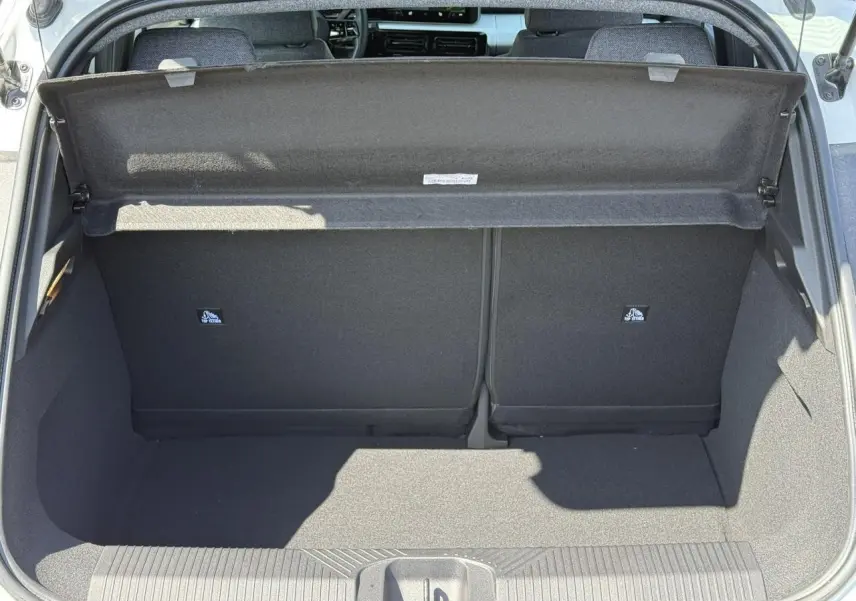 Coffre ouvert vu de l'arrière d'une Renault R5 E-Tech Electrique blanc nacré, intérieur noir et tablette de séparation.