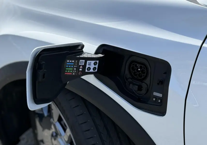 Prise de recharge ouverte côté gauche sur Renault R5 E-Tech blanc nacré, avec jante acier 18 pouces visible.