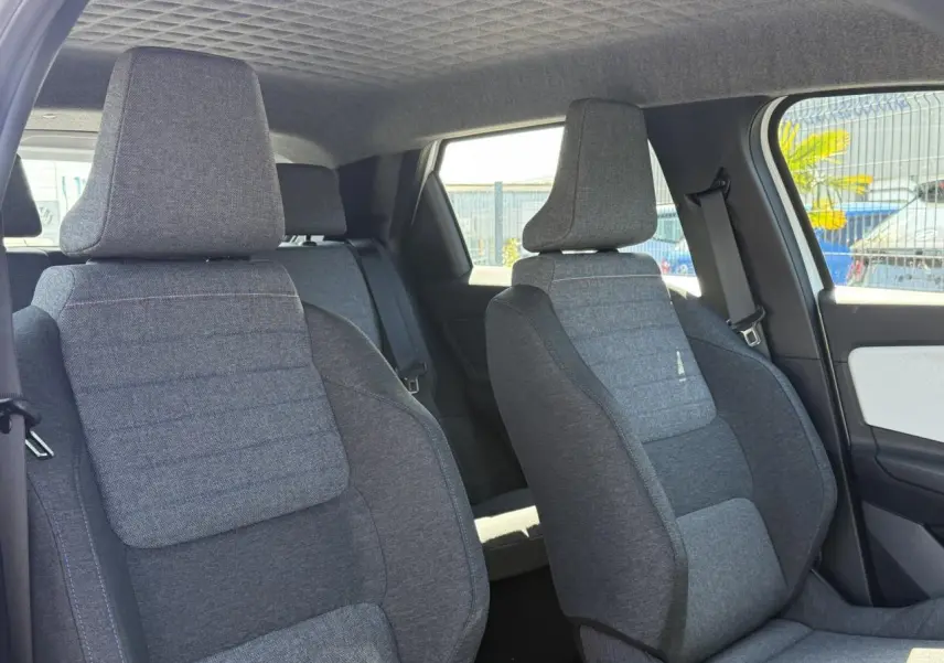 Vue intérieure des sièges avant en textile gris matelassé avec surpiqûres bleu, blanc, rouge dans une Renault R5 E-Tech blanc nacré.