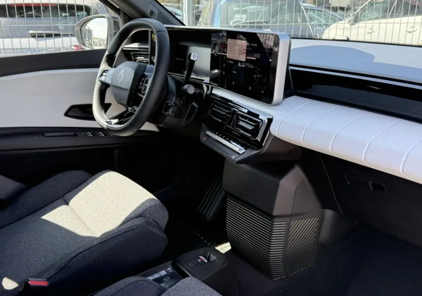 Vue intérieure côté conducteur de la Renault R5 E-Tech 2026, tableau de bord blanc nacré et sièges textile gris matelassé.