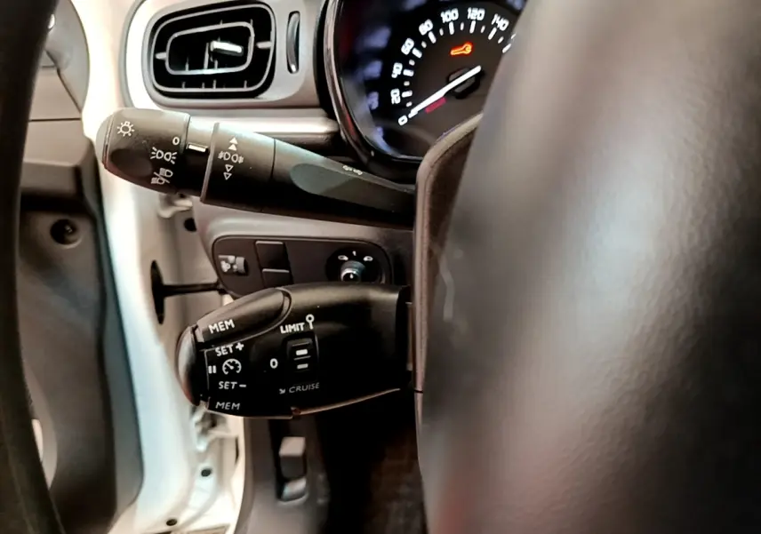 Gros plan sur la commande de régulateur de vitesse et clignotants côté gauche du volant d’une Citroën C3 blanche 2021.