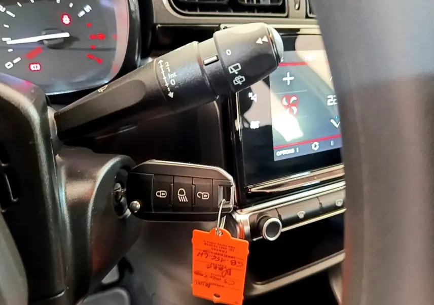 Gros plan intérieur sur le tableau de bord et la clé insérée d'une Citroën C3 blanche, avec écran tactile et commandes visibles.