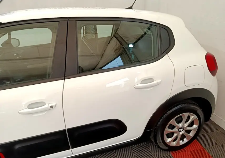 Vue latérale droite d'une Citroën C3 blanche 2021 avec protections noires sur les portières et jantes alliage.
