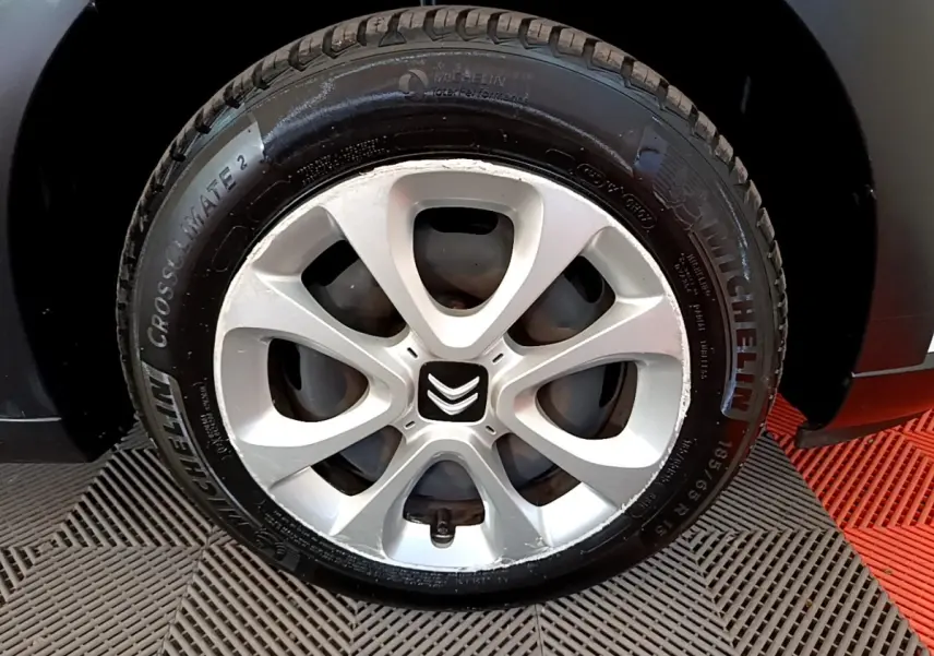 Gros plan sur la roue avant droite d'une Citroën C3 blanche, mettant en valeur la jante en alliage et le pneu Michelin.