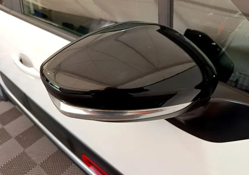 Rétroviseur noir avec clignotant intégré sur la porte blanche côté gauche d'une Citroën C3 2021.